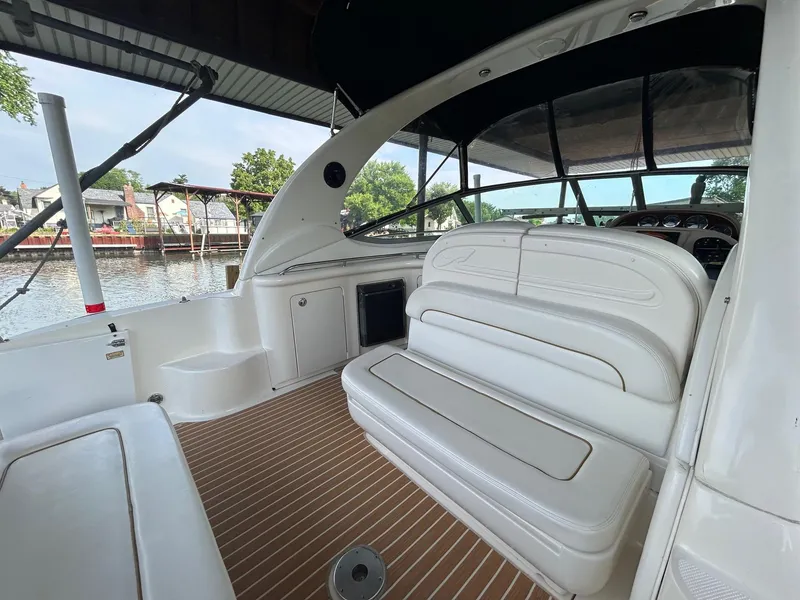 Slide: The Image of 2002 Sea Ray 300 Sundancer boat interior with white seating and wood flooring. - 10