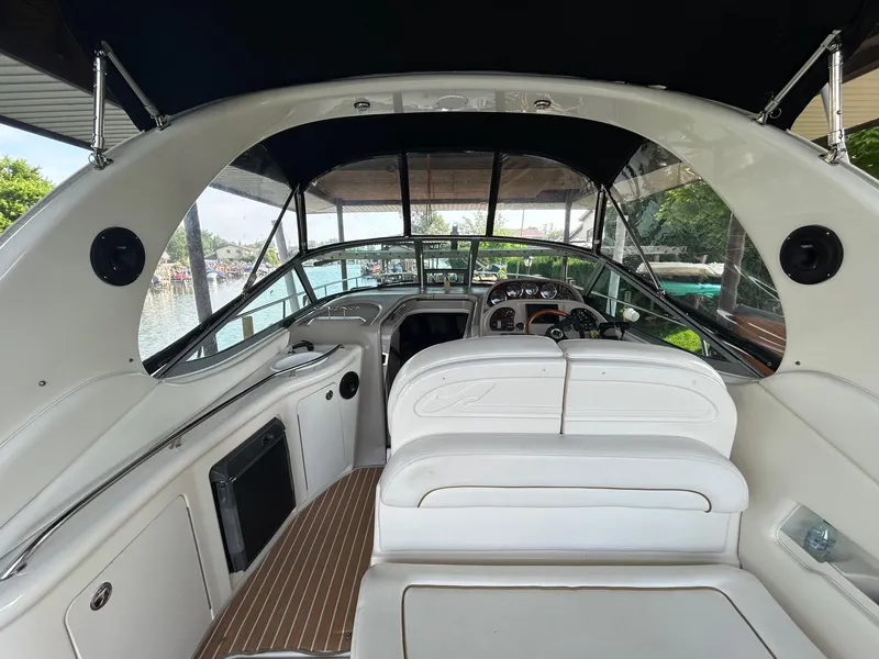 Slide: The Image of 2002 Sea Ray 300 Sundancer boat interior with white seating and dashboard view. - 11