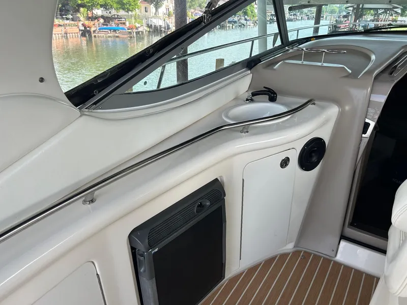 Slide: The Image of 2002 Sea Ray 300 Sundancer interior with sink and mini fridge, overlooking marina. - 12