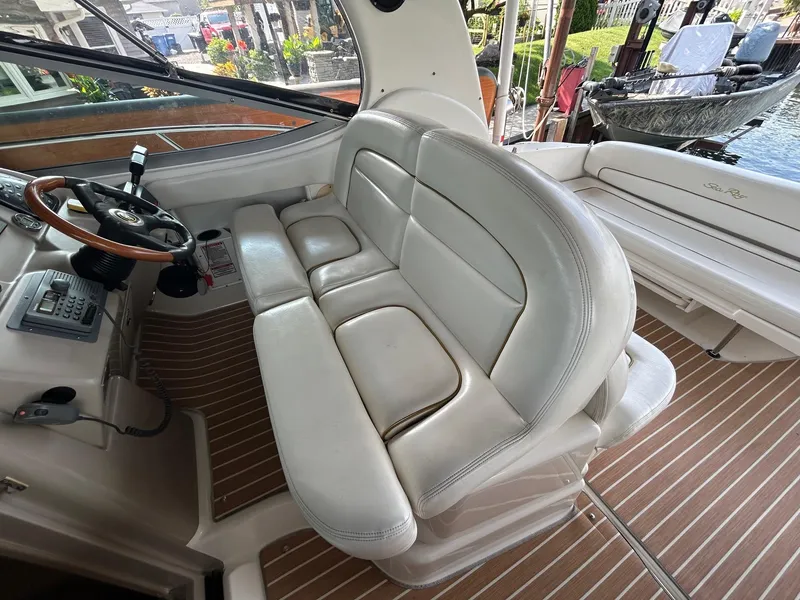 Slide: The Image of 2002 Sea Ray 300 Sundancer cockpit with white leather seating and wooden flooring. - 13