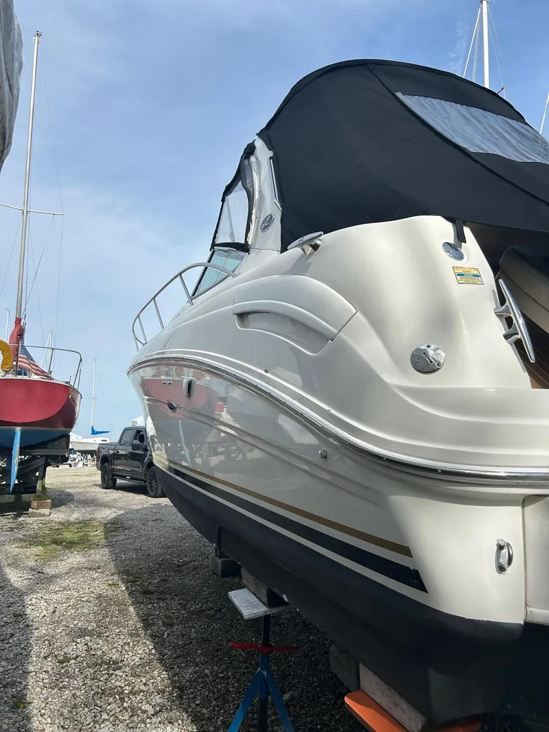 Slide: The Image of 2002 Sea Ray 300 Sundancer boat on dry dock, side view with black canopy. - 2