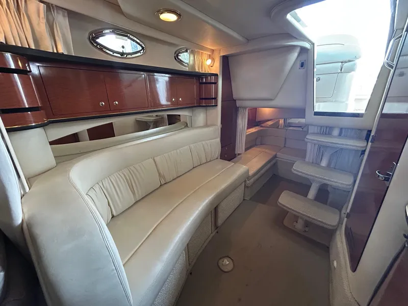Slide: The Image of Interior of 2002 Sea Ray 300 Sundancer yacht with beige seating and wooden cabinets. - 23