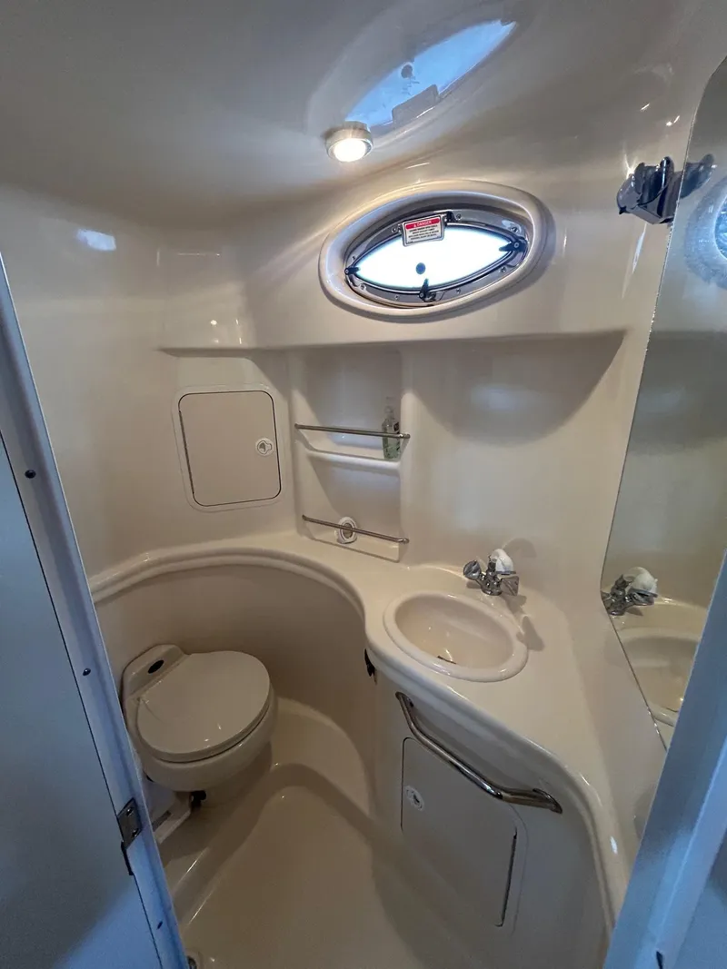 Slide: The Image of Compact bathroom in 2002 Sea Ray 300 Sundancer boat with sink, toilet, and porthole window. - 25