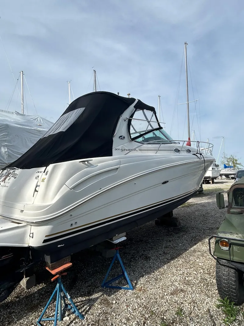 Slide: The Image of 2002 Sea Ray 300 Sundancer boat on stands, covered, in a marina setting. - 4