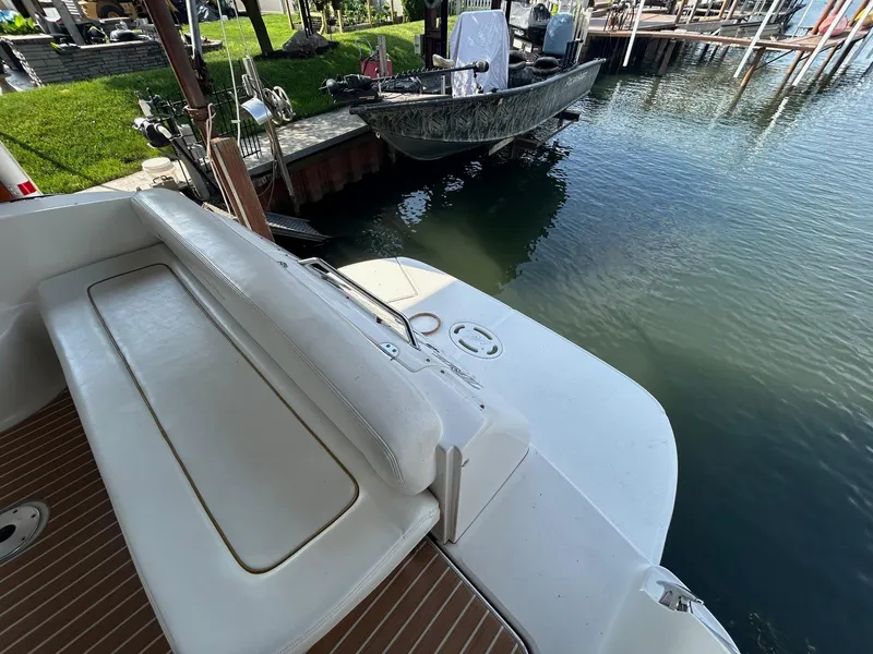 Slide: The Image of 2002 Sea Ray 300 Sundancer boat docked, featuring white seating and wooden deck. - 8
