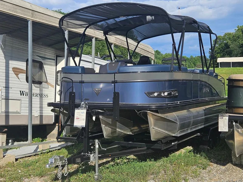 Slide: The Image of 2025 Tahoe Pontoon Cascade Cruise Rear Bench, blue, parked near RVs under a canopy. - 2