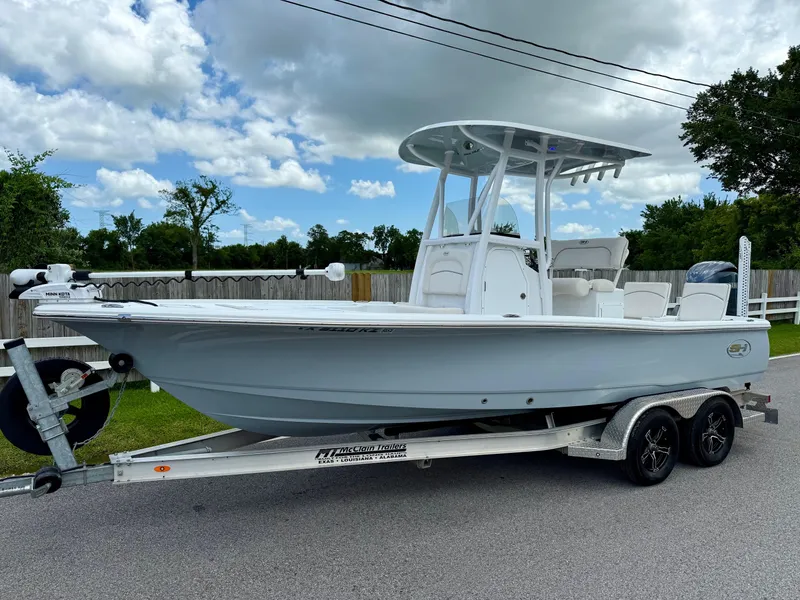 Slide: The Image of 2023 Sea Hunt BX22 boat on trailer, parked on a road under a cloudy sky. - 1