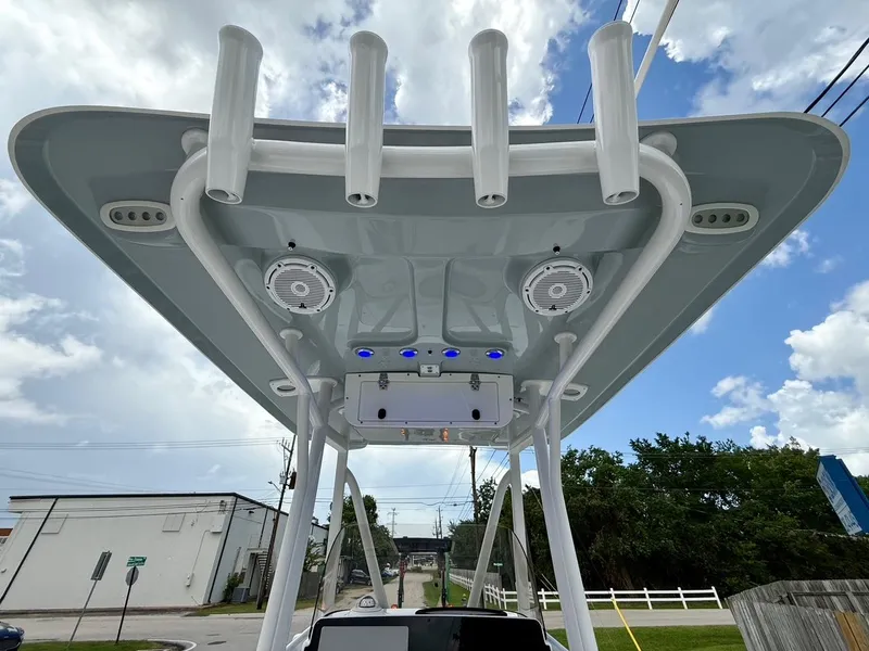 Slide: The Image of 2023 Sea Hunt BX22 boat T-top with rod holders and speakers under a cloudy sky. - 12