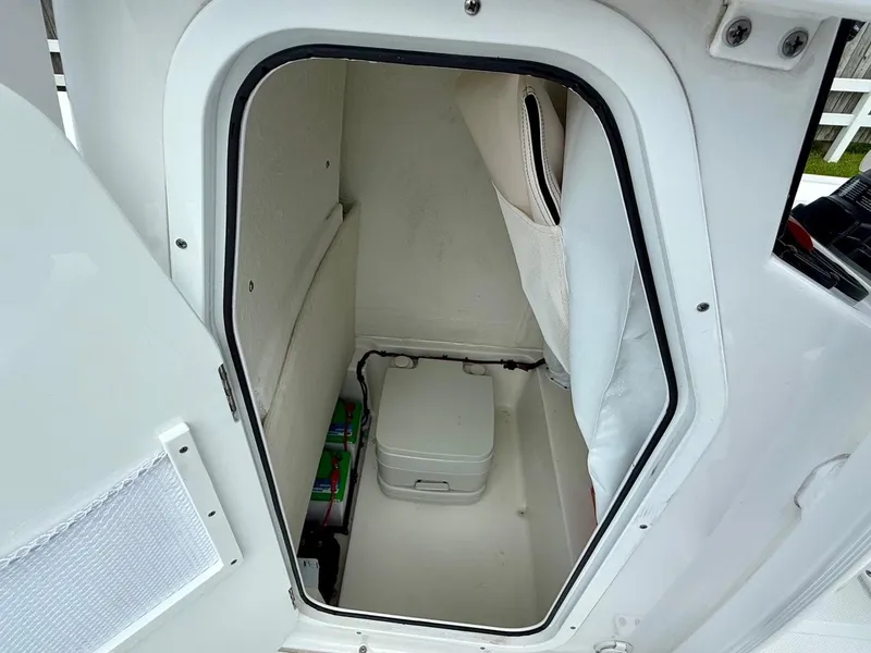 Slide: The Image of 2023 Sea Hunt BX22 boat storage compartment with portable toilet and battery storage. - 14