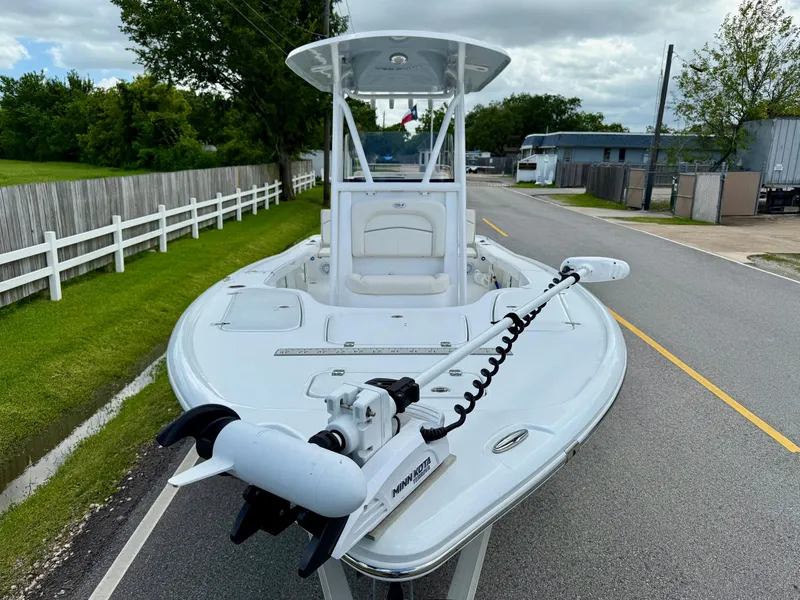 Slide: The Image of 2023 Sea Hunt BX22 boat with trolling motor on a road, surrounded by greenery. - 6