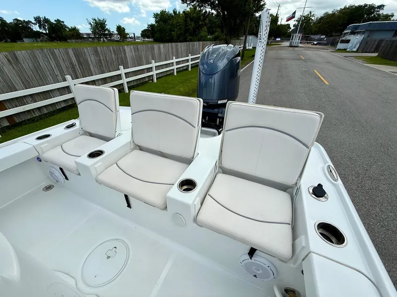 Slide: The Image of 2023 Sea Hunt BX22 boat with three cushioned seats and outboard motor, parked on a road. - 7
