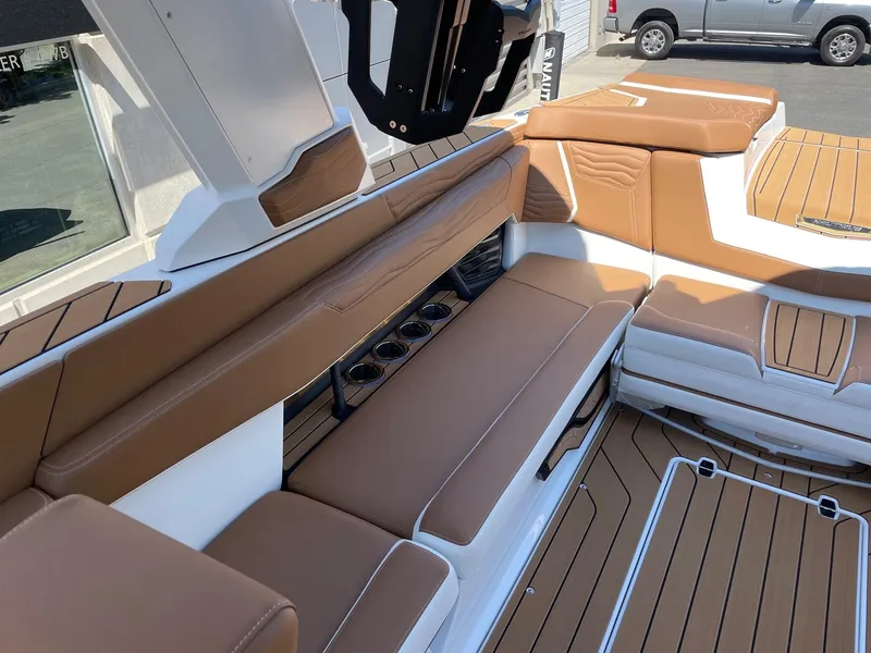Slide: The Image of 2025 Nautique Super Air Nautique G25 interior with tan seating and cup holders. - 7