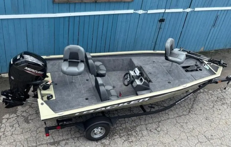 Slide: The Image of 2025 Tracker Pro Team 175 boat with Mercury engine, parked by a blue wooden wall. - 4