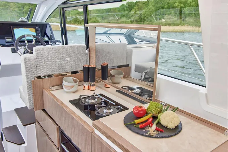 Slide: The Image of Sealine C335V 2024 yacht kitchen with stove, fresh vegetables, and scenic water view. - 12