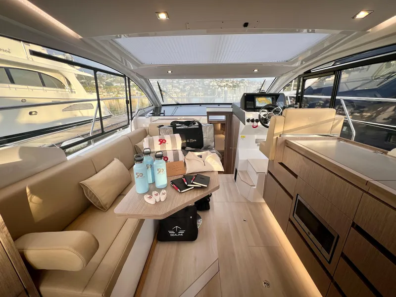 Slide: The Image of 2024 Sealine C335V yacht interior with modern design, featuring seating, helm, and kitchen area. - 7