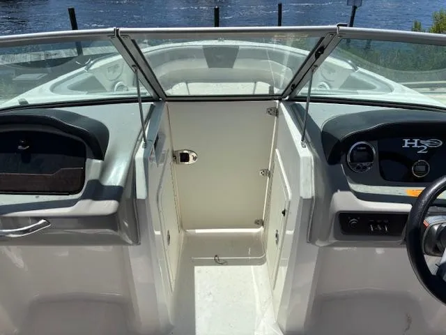 Slide: The Image of 2019 Chaparral 210 Deluxe boat interior with dashboard and open windshield, near water. - 8