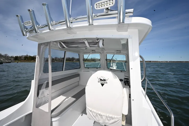 Slide: The Image of 2026 Steiger Craft 23 Miami boat interior with seating and steering, on calm water. - 13