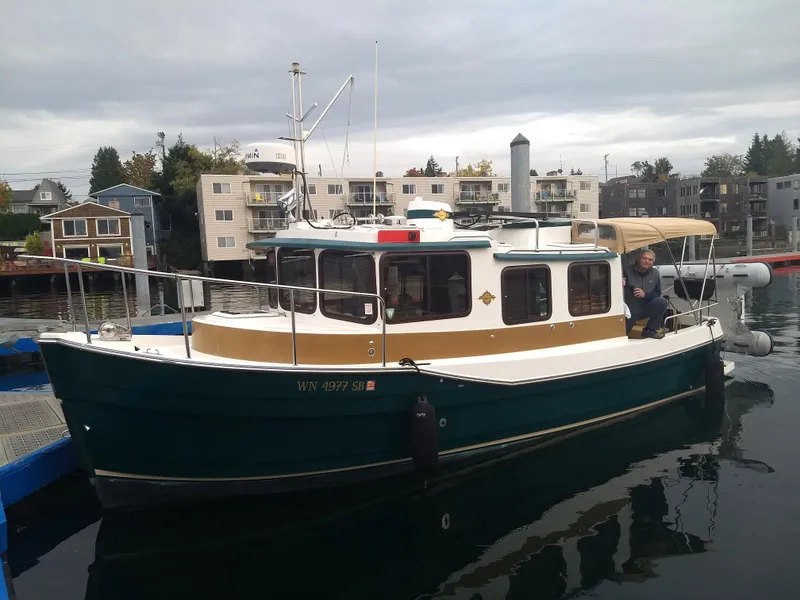 The Image of 2014 Ranger Tugs R-27 boat docked in a marina with residential backdrop. - 0