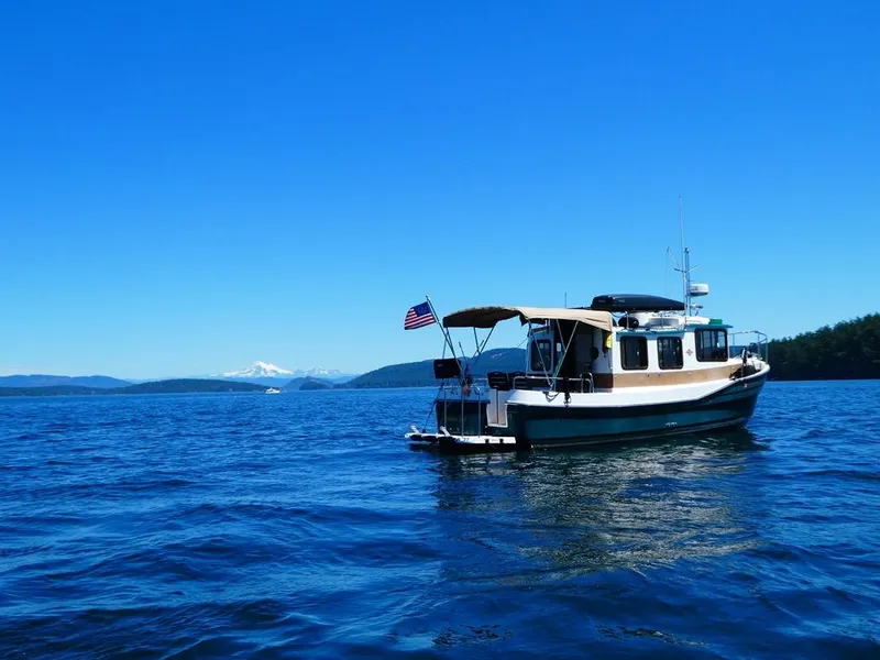 Slide: The Image of 2014 Ranger Tugs R-27 boat on blue water with scenic mountain backdrop. - 2