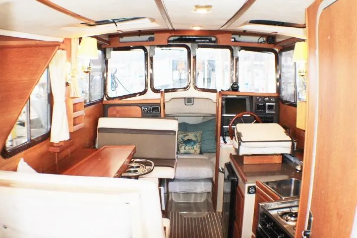 Slide: The Image of Interior of 2014 Ranger Tugs R-27 boat, featuring cozy seating and compact kitchen area. - 23