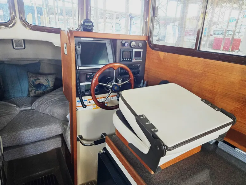 Slide: The Image of 2014 Ranger Tugs R-27 interior with helm, steering wheel, and cozy seating area. - 24