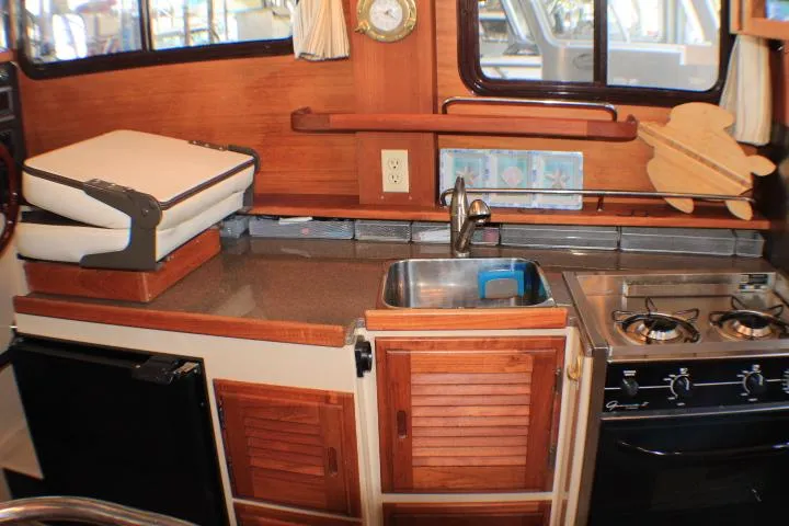 Slide: The Image of Compact kitchen area in a 2014 Ranger Tugs R-27 boat with stove and sink. - 38