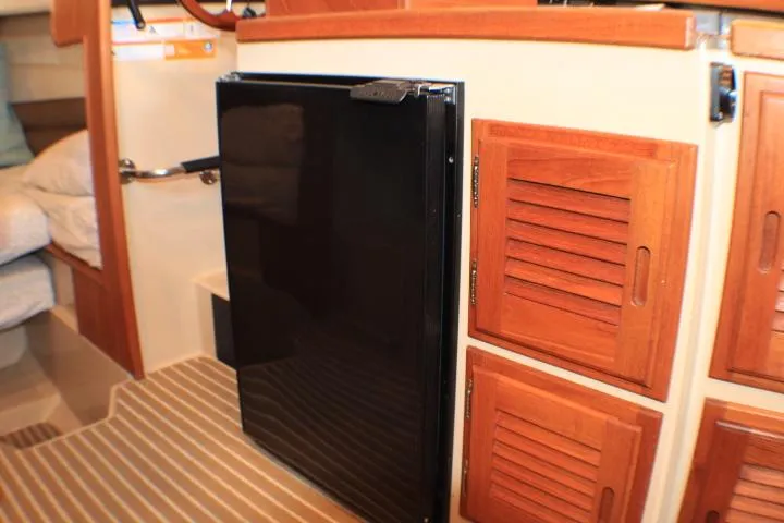 Slide: The Image of 2014 Ranger Tugs R-27 interior with wooden cabinets and a black refrigerator. - 40