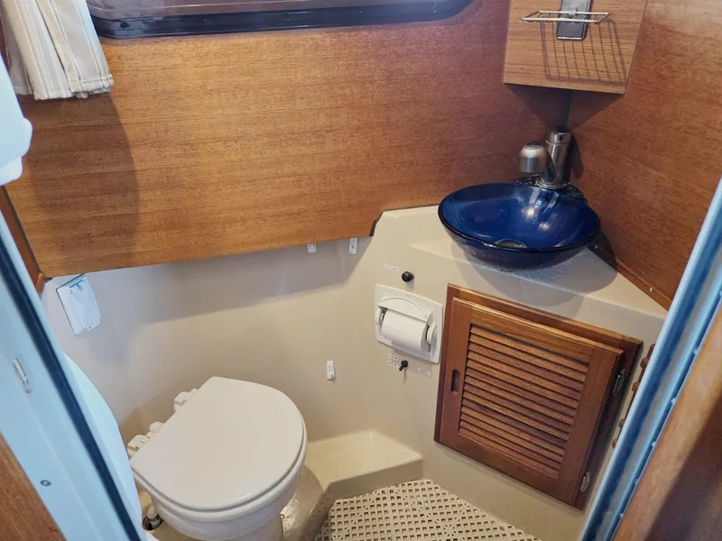 Slide: The Image of 2014 Ranger Tugs R-27 boat bathroom with wooden cabinetry and blue glass sink. - 49