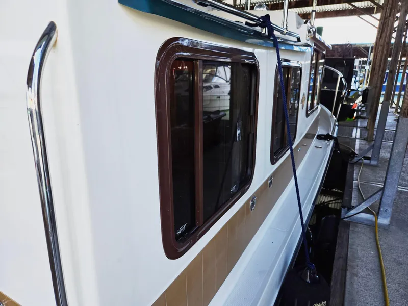 Slide: The Image of 2014 Ranger Tugs R-27 boat docked, side view with windows and railing. - 6