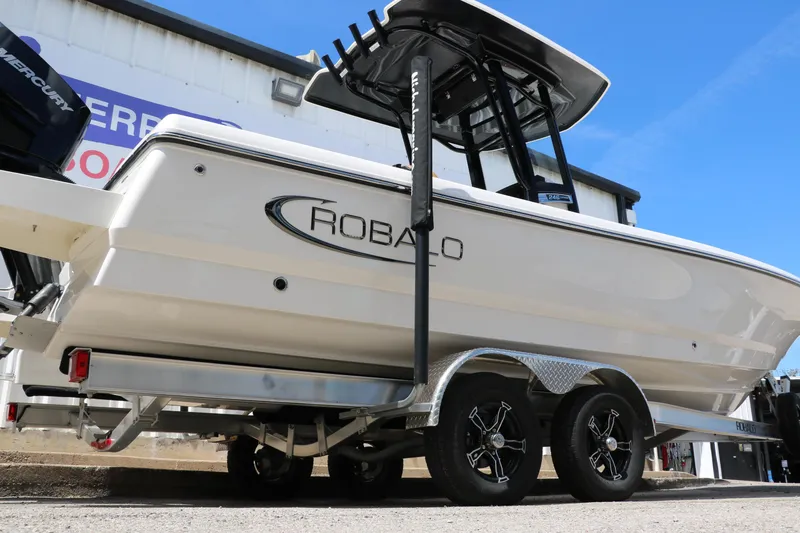 Slide: The Image of 2025 Robalo 246 Cayman boat on trailer, side view, under clear blue sky. - 2