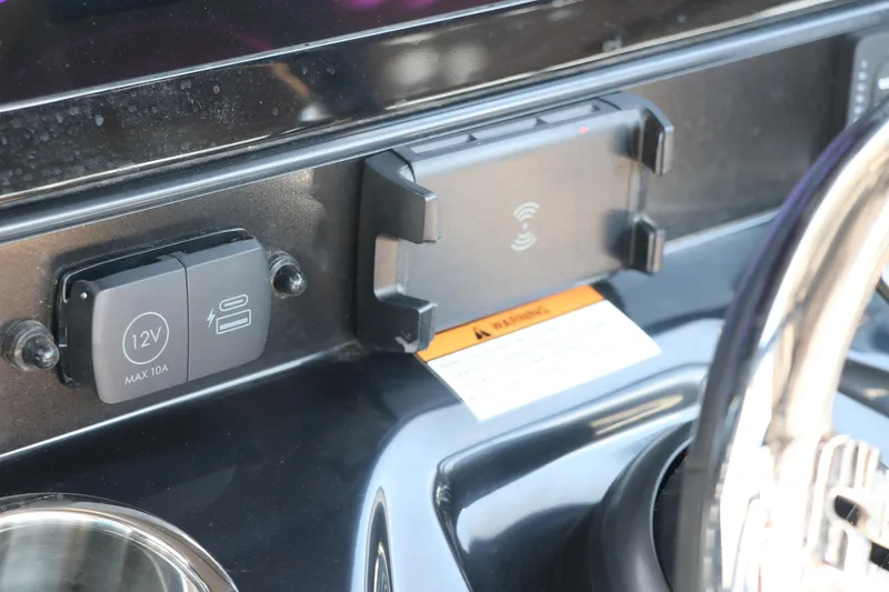 Slide: The Image of 2025 Robalo 246 Cayman dashboard with 12V outlet and wireless charging pad. - 38