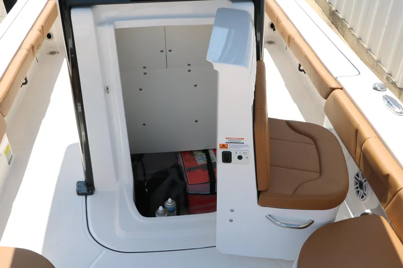 Slide: The Image of 2025 Robalo 246 Cayman boat interior storage compartment with tan seating and safety equipment. - 45