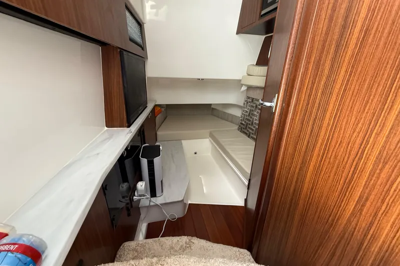 Slide: The Image of 2022 Pursuit S 358 Sport cabin interior with wood finish and fishing rods. - 30