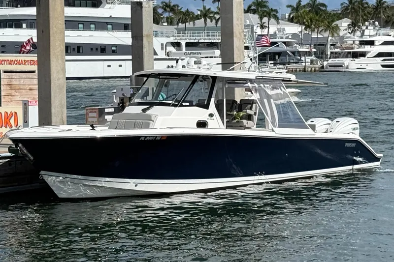 Slide: The Image of 2022 Pursuit S 358 Sport boat docked in marina, covered engines, urban backdrop. - 49