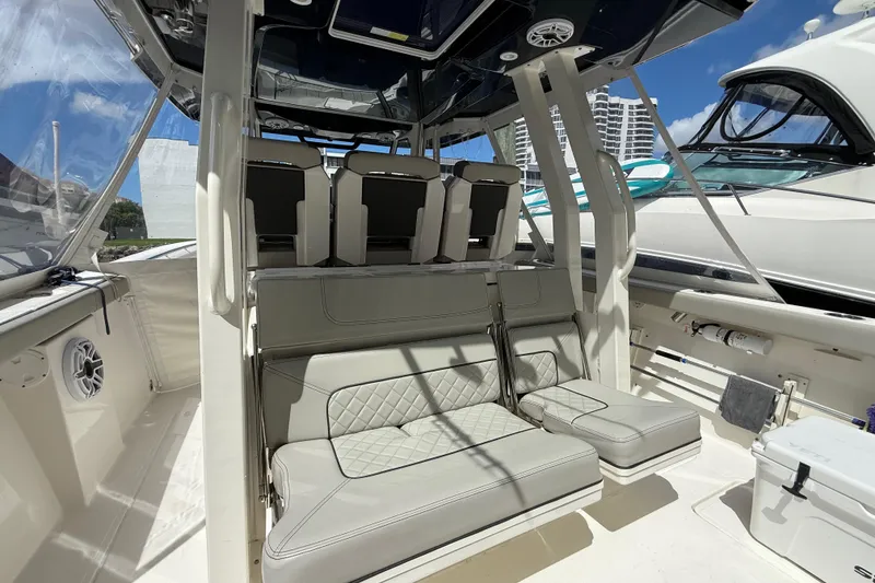 Slide: The Image of 2022 Pursuit S 358 Sport boat interior with seating and storage, docked under clear blue sky. - 7
