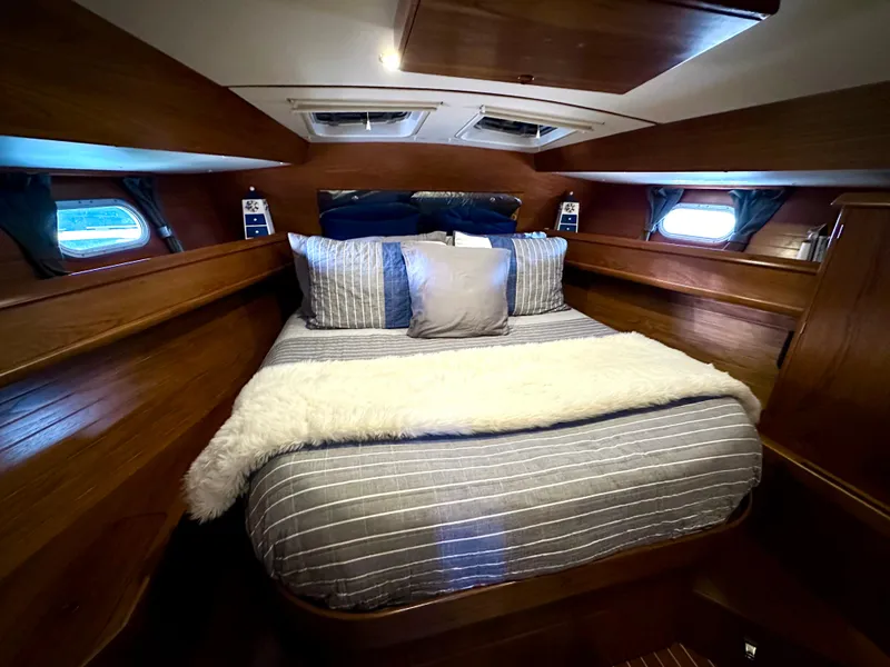 Slide: The Image of Cozy cabin interior of 2000 Jeanneau Sun Odyssey 45.2 with striped bedding and wooden finish. - 4