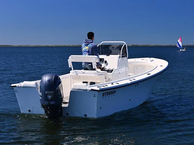 Slide: The Image of 2026 Steiger Craft 21 Tournament boat on water, with person steering, clear blue sky. - 8