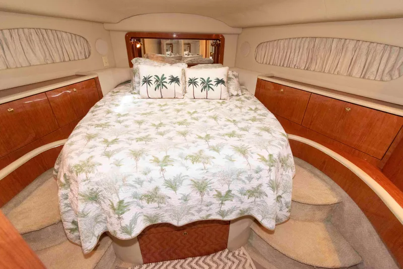 Slide: The Image of Luxurious 2000 Sea Ray 420 Aft Cabin bedroom with palm-themed bedding and elegant wood cabinetry. - 20