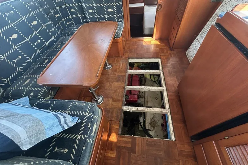 Slide: The Image of Interior of 1978 Albin 36 Trawler with open engine hatch, wooden table, and patterned seating. - 18