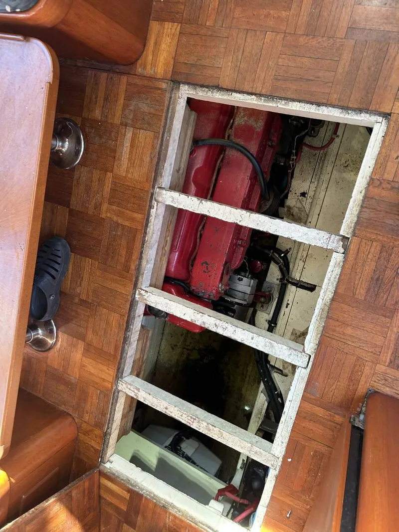 Slide: The Image of 1978 Albin 36 Trawler engine compartment with red engine, visible through open floor panel. - 19