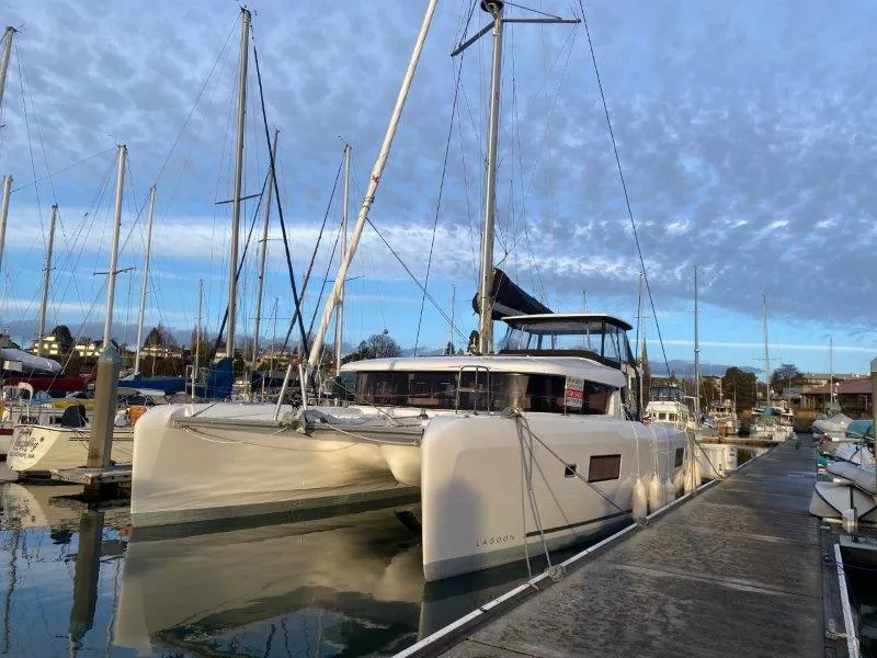 The Image of 2024 Lagoon 42 catamaran docked at a marina under a cloudy sky. - 0