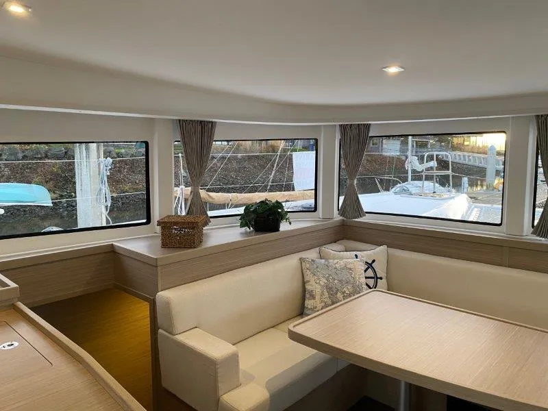 Slide: The Image of Interior of 2024 Lagoon 42 catamaran with modern seating and large windows. - 1