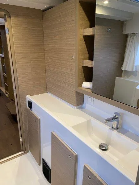 Slide: The Image of Modern bathroom in 2024 Lagoon 42 catamaran with sleek sink, mirror, and wooden cabinetry. - 12