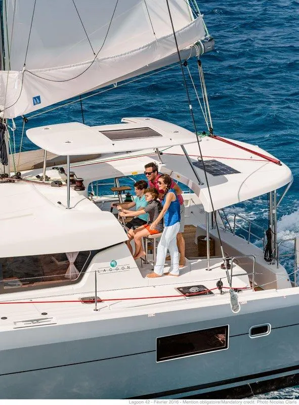 Slide: The Image of Family sailing on a 2024 Lagoon 42 catamaran in clear blue waters. - 37
