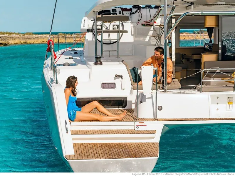 Slide: The Image of 2024 Lagoon 42 catamaran with people relaxing on deck in turquoise waters. - 39
