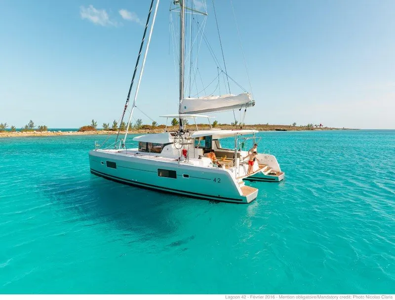Slide: The Image of 2024 Lagoon 42 catamaran sailing in clear turquoise waters near a tropical island. - 42