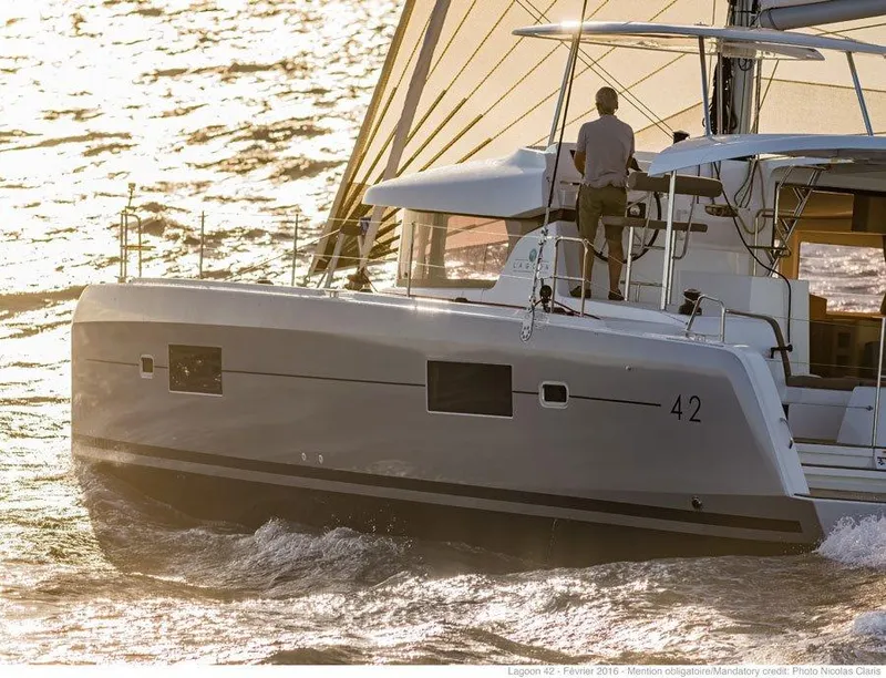 Slide: The Image of 2024 Lagoon 42 sailing catamaran on the water at sunset. - 43