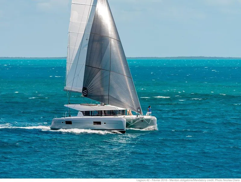 Slide: The Image of 2024 Lagoon 42 sailing catamaran on turquoise ocean waters. - 44