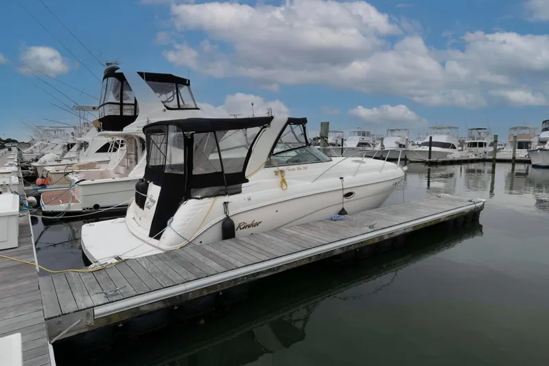 The Image of 2004 Rinker Fiesta Vee 342 docked at marina under blue sky. - 0