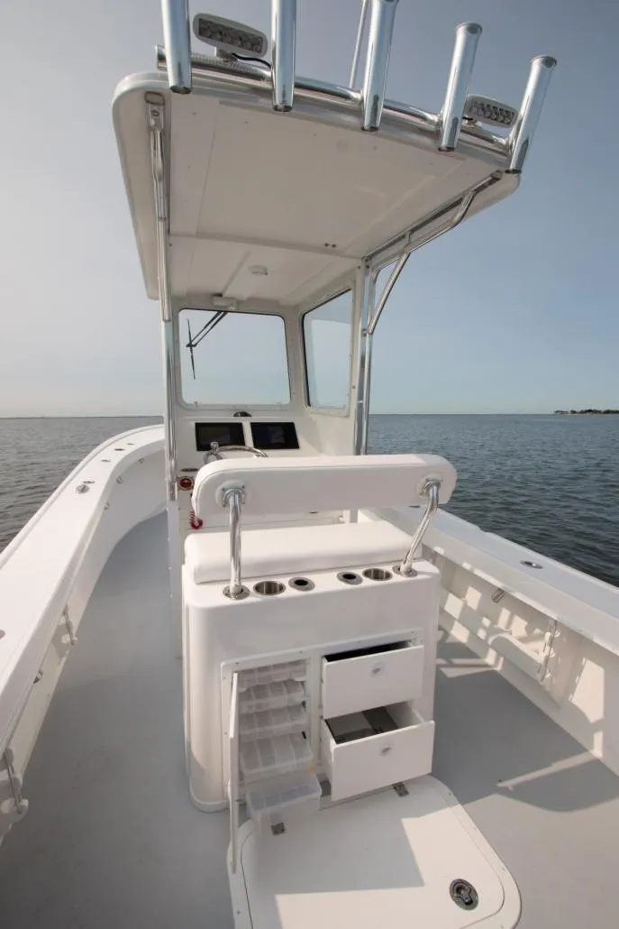 Slide: The Image of 2026 Steiger Craft 23 Chatham boat interior with helm and storage, on calm water. - 7